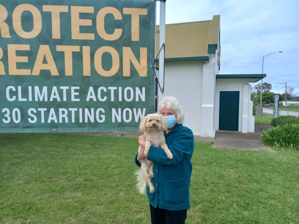 Picture of woman and dog next to sign about climate action